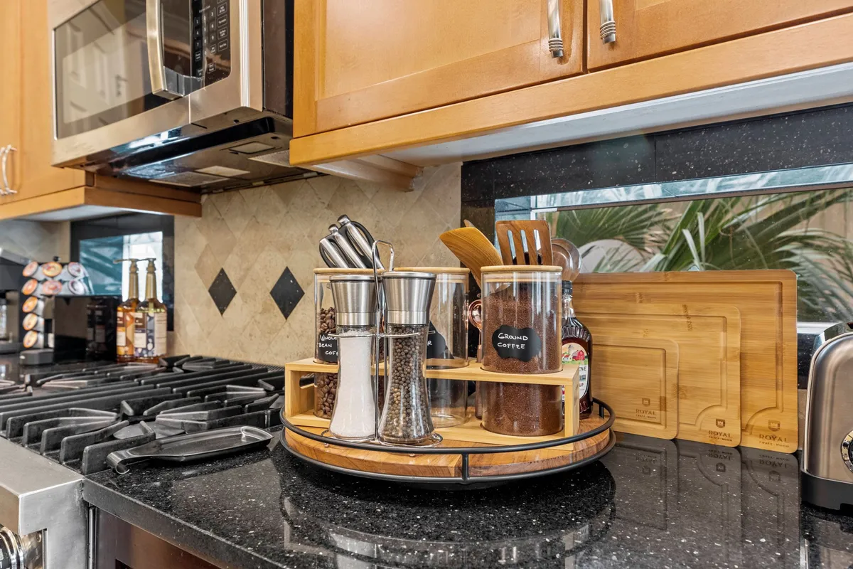 A cozy kitchen scene highlighting a countertop spice rack, sleek stainless steel appliances, and colorful bottles. The layout is organized and conducive to entertaining, with a warm and inviting mood that suggests both functionality and enjoyment during meal prep or gatherings.