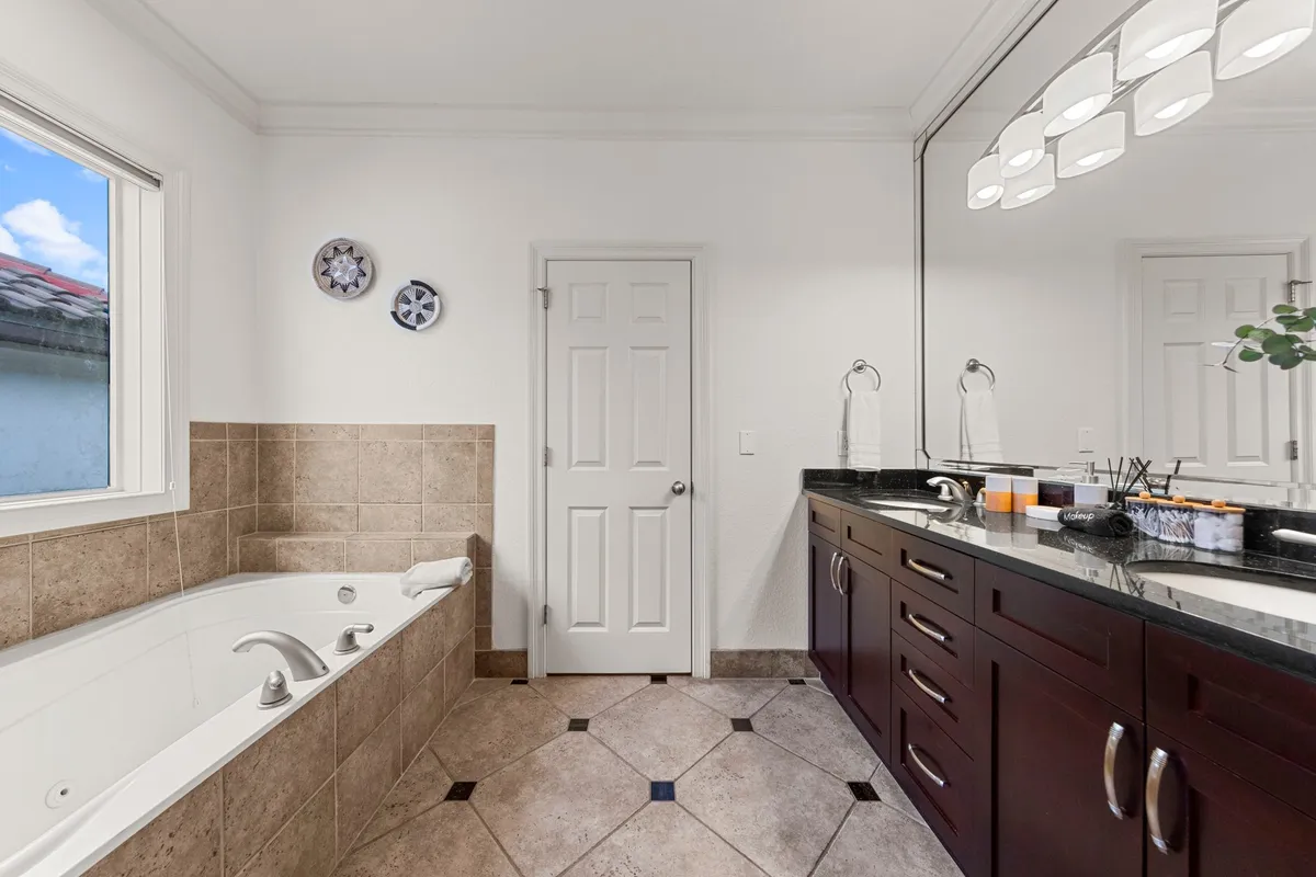 A tranquil bathroom with a deep soaking bathtub, dual sink vanity, ample counter space, and decorative wall plates. The light and decor create a spa-inspired atmosphere ideal for relaxation and self-care.